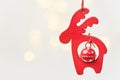 Wooden Christmas ornament red deer with bell hanging on white background with golden garland bokeh lights Royalty Free Stock Photo