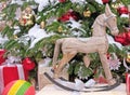 Wooden Christmas rocking horse next to a decorated Christmas tree.