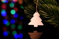 Wooden christmas toy hanging on a spruce branch. Card. Magic bright background. Reflection in black glass