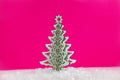 Wooden Christmas tree with artificial snow tree on pink background with copy space. Christmas tree, minimal New Year s card. Holid