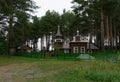 Wooden church in a village in a forest surrounded by pine trees. Two domes of gold and silver, a bell tower. Modern Royalty Free Stock Photo