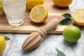 Wooden citrus reamer, fresh lemons and lime on white marble table Royalty Free Stock Photo