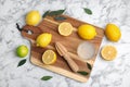 Wooden citrus reamer, juice, fresh lemons and lime on white marble table, flat lay Royalty Free Stock Photo