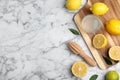 Wooden citrus reamer, juice, fresh lemons and lime on white marble table, flat lay. Space for text Royalty Free Stock Photo