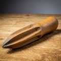 Wooden citrus reamer on a textured wooden surface. The tool has a rounded handle Royalty Free Stock Photo