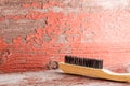 Wooden cleaning brush against red ragged wall