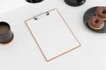 Wooden clipboard mockup with a coffee, donuts and a lamp on a white table