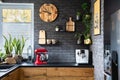 Clock on black brick wall in trendy kitchen with red kitchen robot