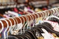 Clothes racks with hangers and with colorful clothes on a blurred background inside shop.