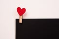 Wooden clothespin with a red heart on a black sheet of paper and a light background Royalty Free Stock Photo