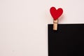 Wooden clothespin with a red heart on a black sheet of paper and a light background Royalty Free Stock Photo