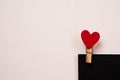 Wooden clothespin with a red heart on a black sheet of paper and a light background Royalty Free Stock Photo