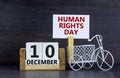 Wooden clothespin with white sheet of paper. Words `Human Rights Day`. Miniature bicycle model. Wooden calendar with the date