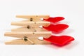 wooden clothespins with a metal spring hold a red heart on a white wooden table background. close-up. selective focus Royalty Free Stock Photo