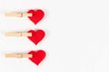 Wooden clothespins with a metal spring hold a red heart on a white wooden table background. close-up. selective focus Royalty Free Stock Photo