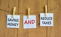 Wooden clothespins with white sheets of paper. Text `saving money and reduce taxes`. Beautiful wooden background. Business conce