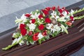Wooden coffin with a beautiful arrangement of flowers on the lid. Funeral ceremony and farewell. Close-up. Top view Royalty Free Stock Photo