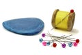 Wooden coil with threads, needle, blue chalk and pins for sewing on a white background