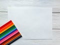 Wooden colored pencils, rainbow style, on the sheet of drawing paper with specific texture, and white wooden background. Copyspace Royalty Free Stock Photo