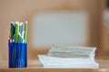 Wooden colorful drawing pencils arranged in plastic jug and stack of copybooks on light copy space background Royalty Free Stock Photo