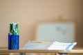 Wooden colorful drawing pencils arranged in plastic jug and stack of copybooks on light copy space background Royalty Free Stock Photo