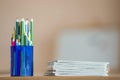 Wooden colorful drawing pencils arranged in plastic jug and stack of copybooks on light copy space background Royalty Free Stock Photo