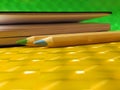 Green and blue pencils and notebook on yellow table Royalty Free Stock Photo