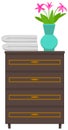 Wooden commode, bedside table. Flower in vase and towels on chest of drawers, home furniture