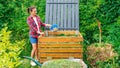 Wooden compost bin close up. A gardener throws lawn clippings and kitchen waste into a DIY compost bin to improve the fertility