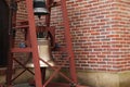 Wooden construction with two old bells near brick wall outdoors