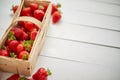 Wooden container with fresh red strawberries. Placed on white table. Royalty Free Stock Photo