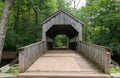 Wooden Covered bridge over a small river in a lush green forest Royalty Free Stock Photo