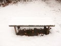 wooden covered public bench snow outside winter grass covered white