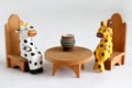 Wooden cow and cheetah are sitting on chairs near the table. Closeup