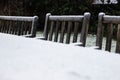 Wooden cozy garden chairs covered in snow in a backyard garden. Royalty Free Stock Photo