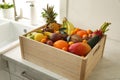 Wooden crate with assortment of exotic fruits on table in kitchen Royalty Free Stock Photo