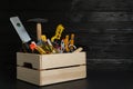 Wooden crate with different carpenter`s tools on black table. Space for text