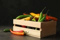 Wooden crate with different chili peppers on grey Royalty Free Stock Photo