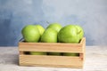 Wooden crate of fresh ripe green apples on white table against blue background, Royalty Free Stock Photo