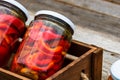 Wooden crate with glass jars with pickled red bell peppers.Preserved food concept, canned vegetables isolated in a rustic Royalty Free Stock Photo