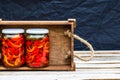 Wooden crate with glass jars with pickled red bell peppers.Preserved food concept, canned vegetables isolated in a rustic Royalty Free Stock Photo