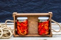 Wooden crate with glass jars with pickled red bell peppers.Preserved food concept, canned vegetables isolated in a rustic Royalty Free Stock Photo