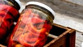 Wooden crate with glass jars with pickled red bell peppers.Preserved food concept, canned vegetables isolated in a rustic