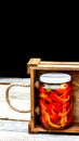 Wooden crate with glass jars with pickled red bell peppers.Preserved food concept, canned vegetables isolated in a rustic Royalty Free Stock Photo