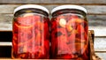 Wooden crate with glass jars with pickled red bell peppers.Preserved food concept, canned vegetables isolated in a rustic