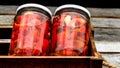 Wooden crate with glass jars with pickled red bell peppers.Preserved food concept, canned vegetables isolated in a rustic Royalty Free Stock Photo