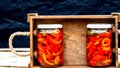 Wooden crate with glass jars with pickled red bell peppers.Preserved food concept, canned vegetables isolated in a rustic