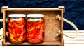 Wooden crate with glass jars with pickled red bell peppers.Preserved food concept, canned vegetables isolated in a rustic