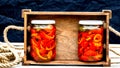 Wooden crate with glass jars with pickled red bell peppers.Preserved food concept, canned vegetables isolated in a rustic Royalty Free Stock Photo