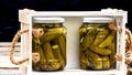 Wooden crate with glass jars with pickles isolated. Preserved food concept, canned vegetables isolated in a rustic composition